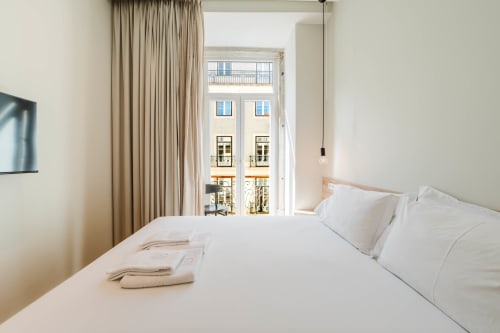 Bright Premium Suite bedroom at GS Chiado Boutique Studios in Lisbon with city views, white bedding, and floor-to-ceiling