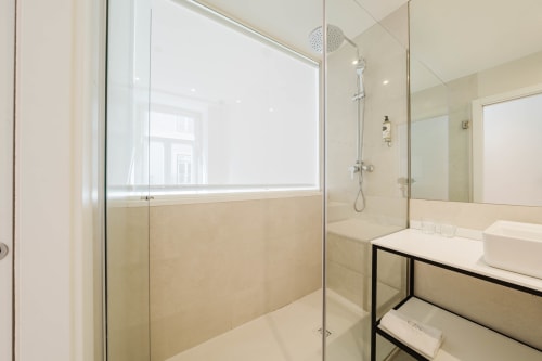 Modern bathroom in GS Chiado Boutique Studios & Suites, Lisbon, with walk-in shower, double sink vanity, and city views