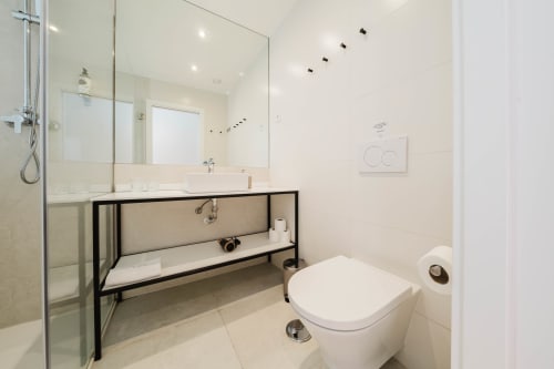 Modern bathroom in GS Chiado Boutique Studios, Lisbon, with glass shower enclosure, minimalist sink vanity, and white ceramic
