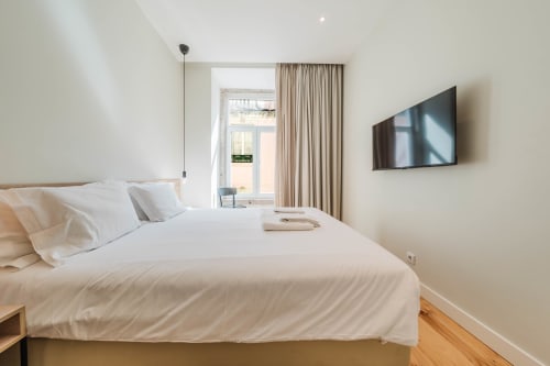 Modern Premium Suite bedroom at GS Chiado Boutique Studios in Lisbon with city view, flat-screen TV, and contemporary
