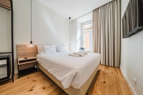 Modern Premium Suite at GS Chiado Boutique in Lisbon with wooden floors, white bed, and city views through floor-to-ceiling