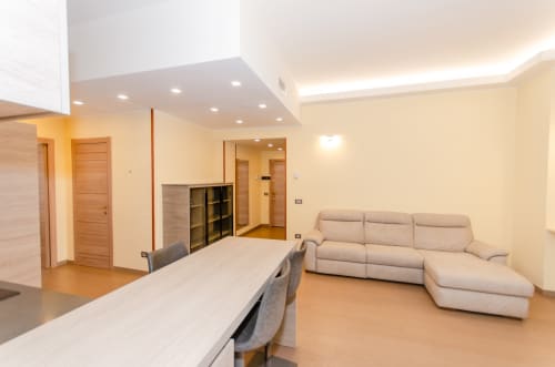 Appartamento moderno a Milano Porta Nuova con divano componibile beige, tavolo da pranzo e spazio living open-concept