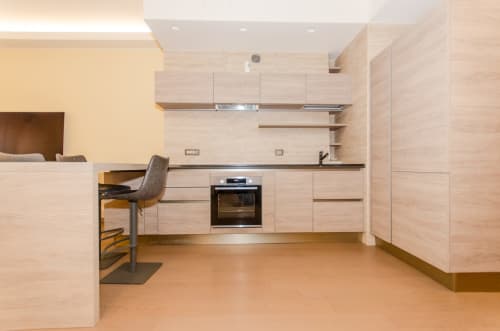 Cucina moderna nell'appartamento Milano Hospitality Porta Nuova Home con mobili in legno chiaro, piano nero e forno incasso