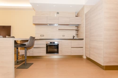 Cucina moderna in Porta Nuova Home, appartamento Milano Hospitality con mobili in legno chiaro e elettrodomestici in acciaio inossidabile