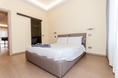 Camera moderna dell'aparthotel Milano Hospitality Porta Nuova con letto queen size, pavimento in legno e arredamento minimalista