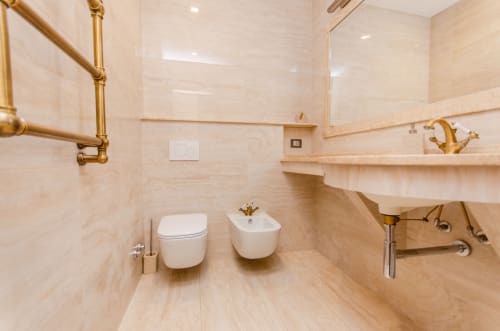 Bagno moderno dell'aparthotel Milano Porta Nuova con piastrelle beige, wc, bidet e finiture in ottone