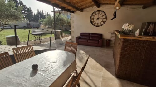 Vaste espace de vie extérieur couvert au gîte Le Mas d'Andiol avec table à manger, coin salon et vue sur le jardin