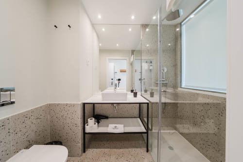 Casa de banho moderna no Liberator Rossio Hotel em Lisboa com pavimento em terrazzo, pia flutuante e chuveiro walk-in