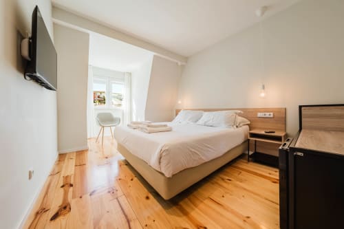 Suite loft moderna no Hotel Liberator Rossio em Lisboa com piso de madeira, cama queen, TV e luz natural