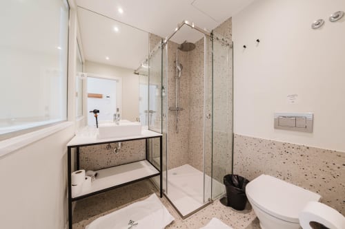 Banheiro moderno na Suíte Loft do Hotel Liberator Rossio, Lisboa, com acabamentos em terrazzo, duche walk-in e design contemporâneo