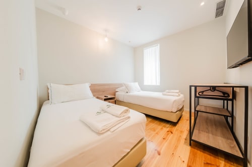 Quarto familiar com duas camas, piso em madeira e iluminação natural no Liberator Rossio Hotel em Lisboa