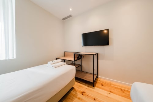 Quarto Familiar no Hotel Liberator Rossio Lisboa com cama, secretária, TV e piso em madeira