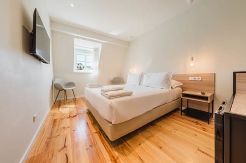 Quarto moderno do Liberator Rossio Hotel em Lisboa com cama queen, piso de madeira, TV na parede e vista para a janela