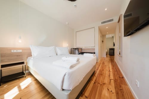 Quarto de família moderno no Hotel Liberator Rossio Lisboa com cama queen, assoalho de madeira e vista para a cidade
