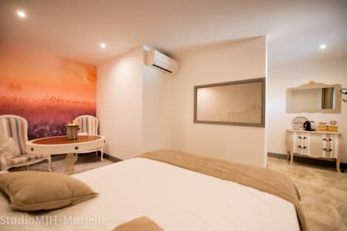 Chambre spacieuse du gîte Le Mas d'Andiol à Plan d'Orgon avec lit queen-size, coin salon, tableau de coucher de soleil et design contemporain
