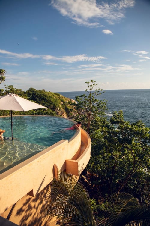 Piscina infinita con vistas al océano en Casa Baori, Puerto Ángel México, acantilados costeros y vegetación tropical