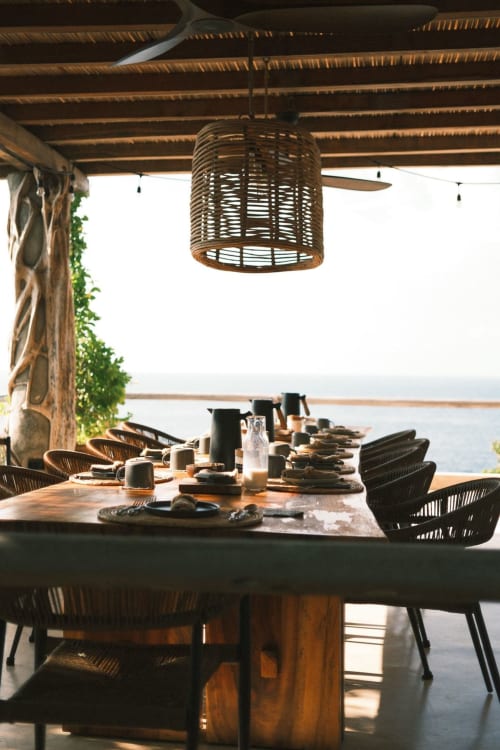 Comedor con vista al océano en Casa Baori, lámpara colgante tejida, vigas de madera y montaje de mesa con vistas a la costa de Puerto Ángel