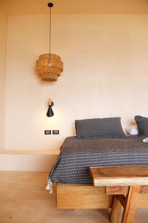 Dormitorio moderno en Casa Baori con lámpara colgante de madera, ropa de cama gris y decoración minimalista en Puerto Ángel