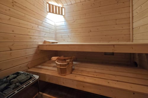 Intérieur de sauna en bois de l'appartement O LIT avec bancs, seau en bois et puits de lumière en France