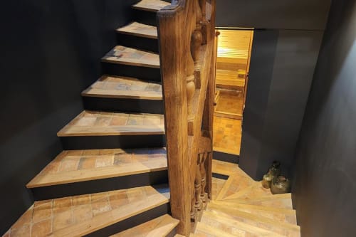 Escalier en bois avec rampe sculptée dans l'appartement O LIT, menant à l'étage avec porte en bois visible