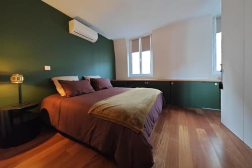 Chambre moderne de l'appartement O LIT avec mur d'accent vert, literie violette, parquet et vue sur la ville