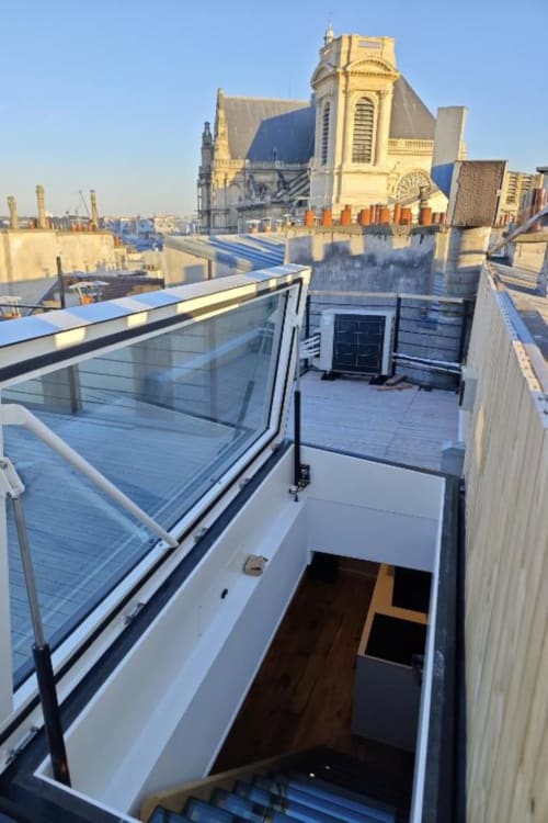 Terrasse contemporaine sur le toit avec balcon vitré de l'appartement O LIT Paris, vue sur l'architecture parisienne historique et la ville