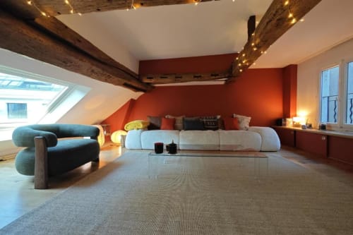 Salon de style loft moderne à l'appartement O LIT avec poutres en bois apparentes, murs accent rouge, mobilier contemporain et