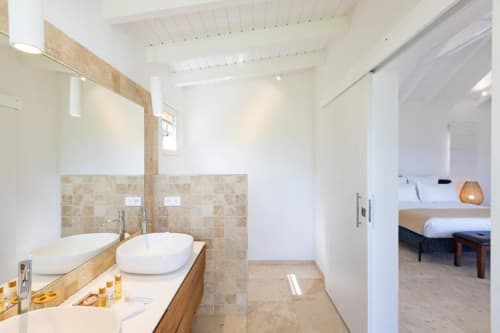 Salle de bain moderne de la villa O LIT avec double vasque, grand miroir et vue vers la chambre