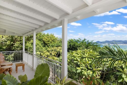 Terrasse de la villa O LIT avec vue sur l'océan, colonnes blanches, plantes tropicales et paysage côtier en France