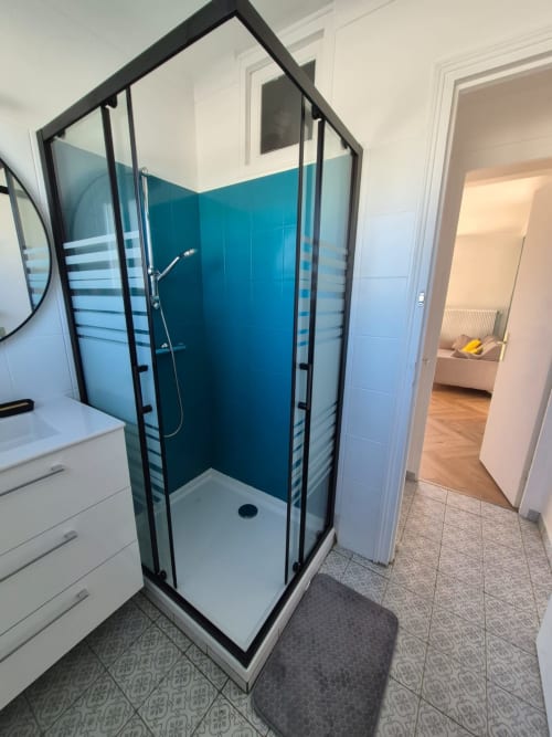 Salle de bain moderne avec douche bleu canard et encadrement noir à l'appartement Accolade de Châteaudun