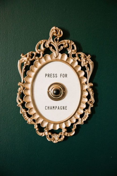 Bouton de sonnette doré ornementé indiquant « Appuyez pour le Champagne » à l'hôtel ARLOÉ à La Rochelle