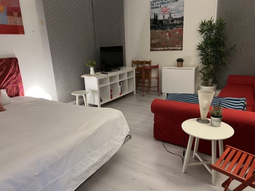 Estudio moderno en casa de Tessa en Matadepera con cama, sofá rojo, escritorio blanco y plantas