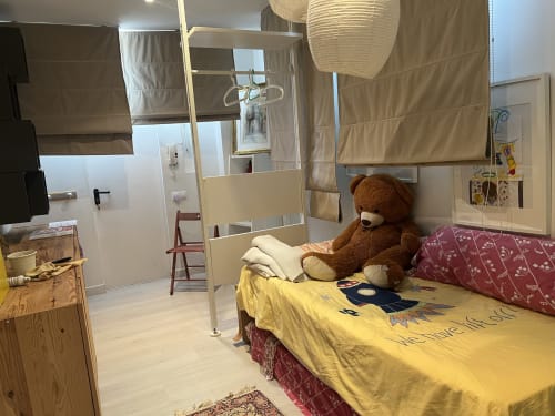 Habitación infantil en los apartamentos Tessa de Matadepera con ropa de cama amarilla, osito de peluche marrón y ducha accesible