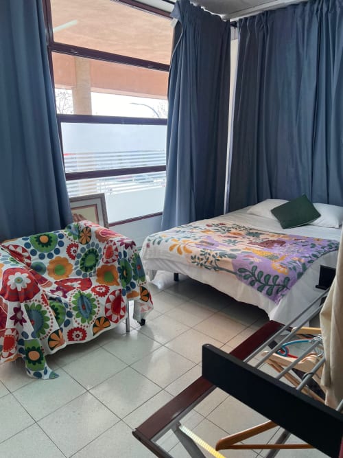 Dormitorio luminoso en los apartamentos Tessa de Sabadell con dos camas, ropa de cama colorida, vistas a la ciudad y comodidades modernas