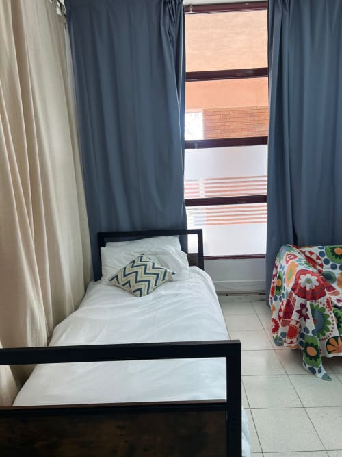Dos camas individuales con marcos negros en apartamento moderno de Sabadell, cortinas azules, vistas a la ciudad