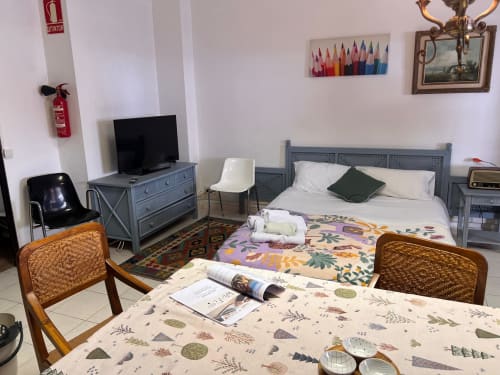 Dormitorio del apartamento Tessa en Sabadell con cama, TV, mesa de comedor y decoración con vista a la ciudad