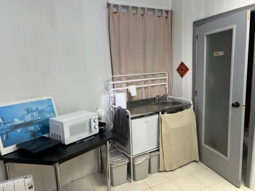 Cocina compacta en el apartamento de Tessa en Sabadell con microondas, fregadero, mininevera, tendedero y puerta del baño