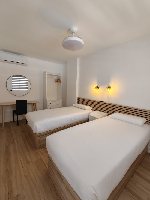 Moderna habitación doble en Bahia Mar Canarias de Telde con ropa de cama blanca, camas de madera, escritorio e iluminación ambiental