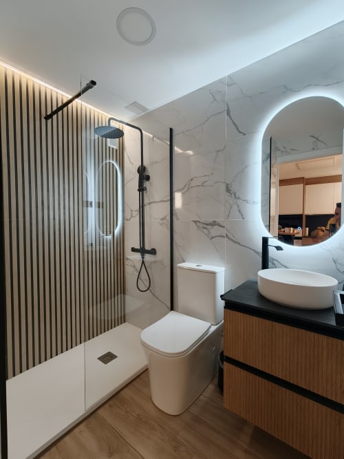 Baño moderno en apartamento Vista Pacifica de Bahia Mar Canarias, Telde con paredes de mármol, ducha de efecto lluvia y espejo circular iluminado