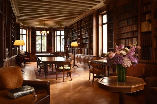 Élégante bibliothèque du Château De Varambon avec bibliothèques en bois du sol au plafond, mobilier en acajou et ambiance rafraîchissante