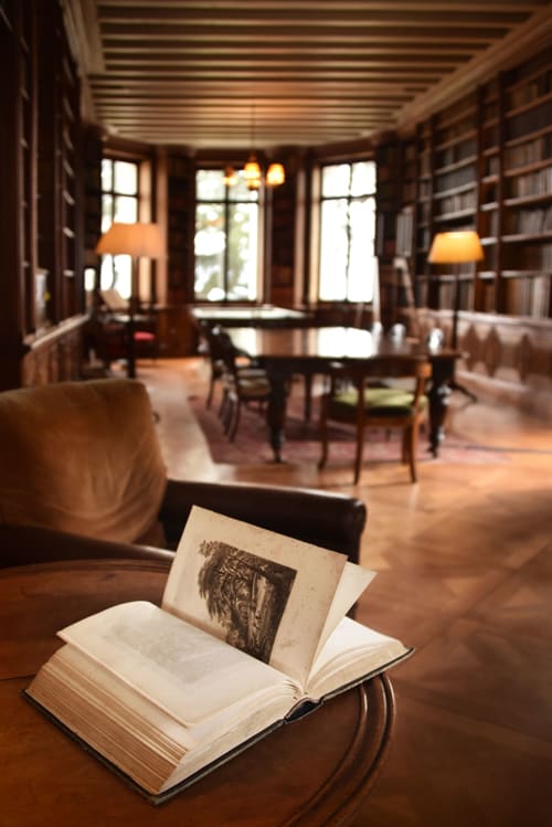 Bibliothèque historique du Château de Varambon avec livre ouvert sur bureau en bois et étagères