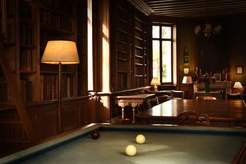 Élégante salle de billard lambrissée au Château De Varambon avec table de jeu, fauteuils en cuir et éclairage chaleureux