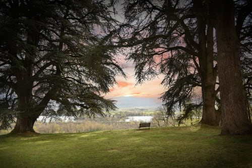 Point de vue pittoresque au Château de Varambon avec anciens arbres encadrant le paysage de la vallée au coucher de soleil