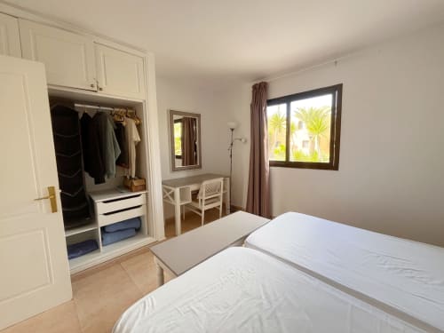 Luminoso dormitorio en FTV Holidays Homes de La Oliva con cama doble, armario, escritorio y ventana con vistas a palmeras