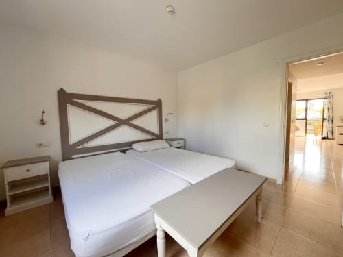 Dormitorio luminoso en FTV Holidays Homes en La Oliva con cama de marco X, ropa de cama blanca y acceso al baño privado