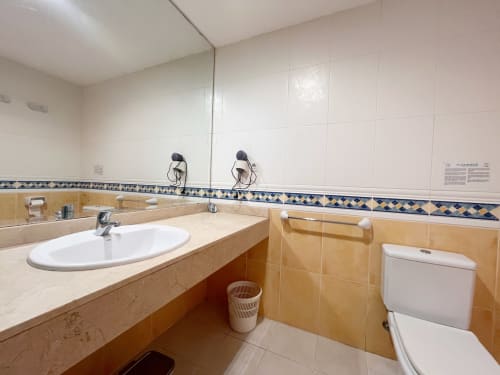 Baño luminoso en FTV Holidays Homes en La Oliva con azulejos beige, lavabo ovalado, inodoro y espejo grande