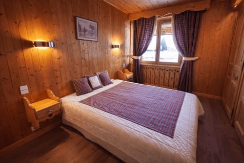 Cozy wooden alpine bedroom at Chez Marion, Notre Dame de Bellecombe, with plaid bedding and mountain view windows