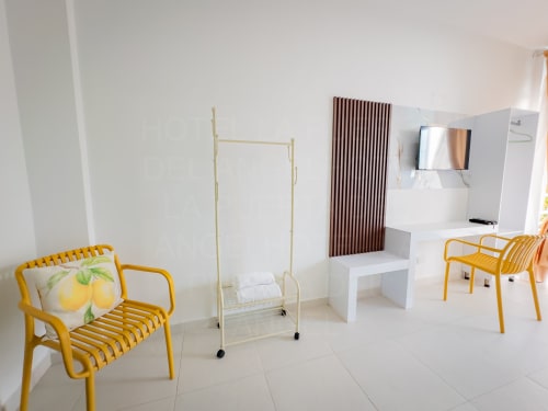 Luminosa habitación moderna en La Puerta del Angel con sillas amarillas, cama individual, muebles blancos y TV en Ricaurte, Colombia