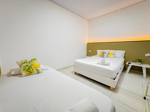 Moderno dormitorio triple en hotel La Puerta del Ángel, Ricaurte, con dos camas, almohadas temática limón y tonos verde oliva