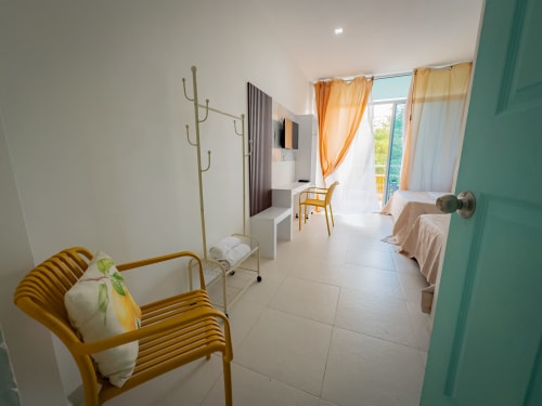 Habitación luminosa en La Puerta del Angel con sillas amarillas, camas gemelas, cortinas naranjas y vistas al río desde el balcón